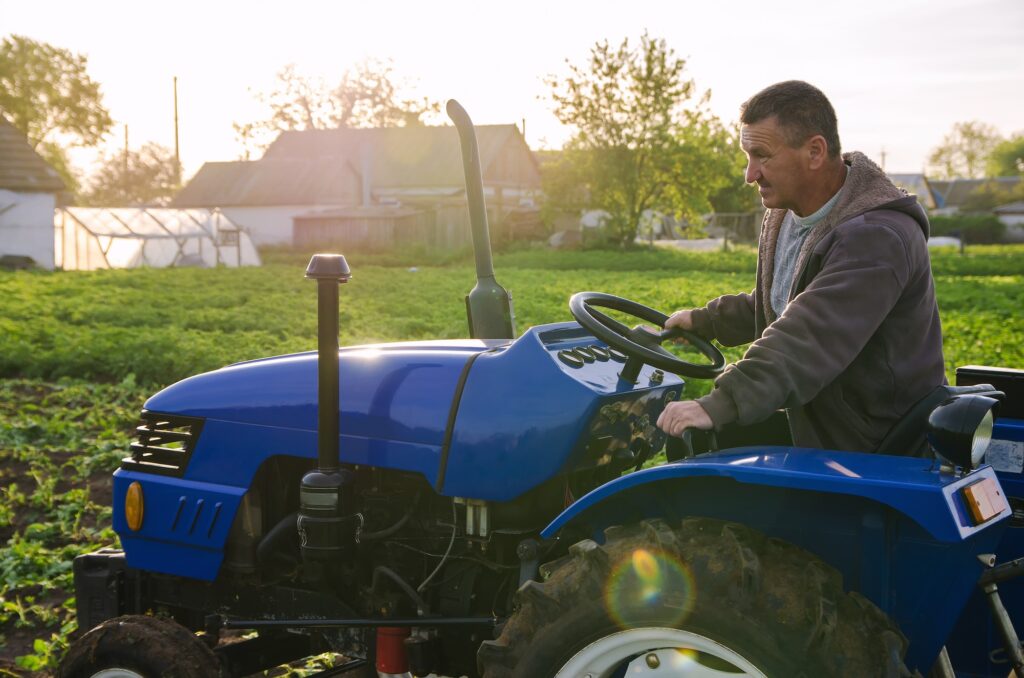 A farmer on a tractor drives across the farm field.